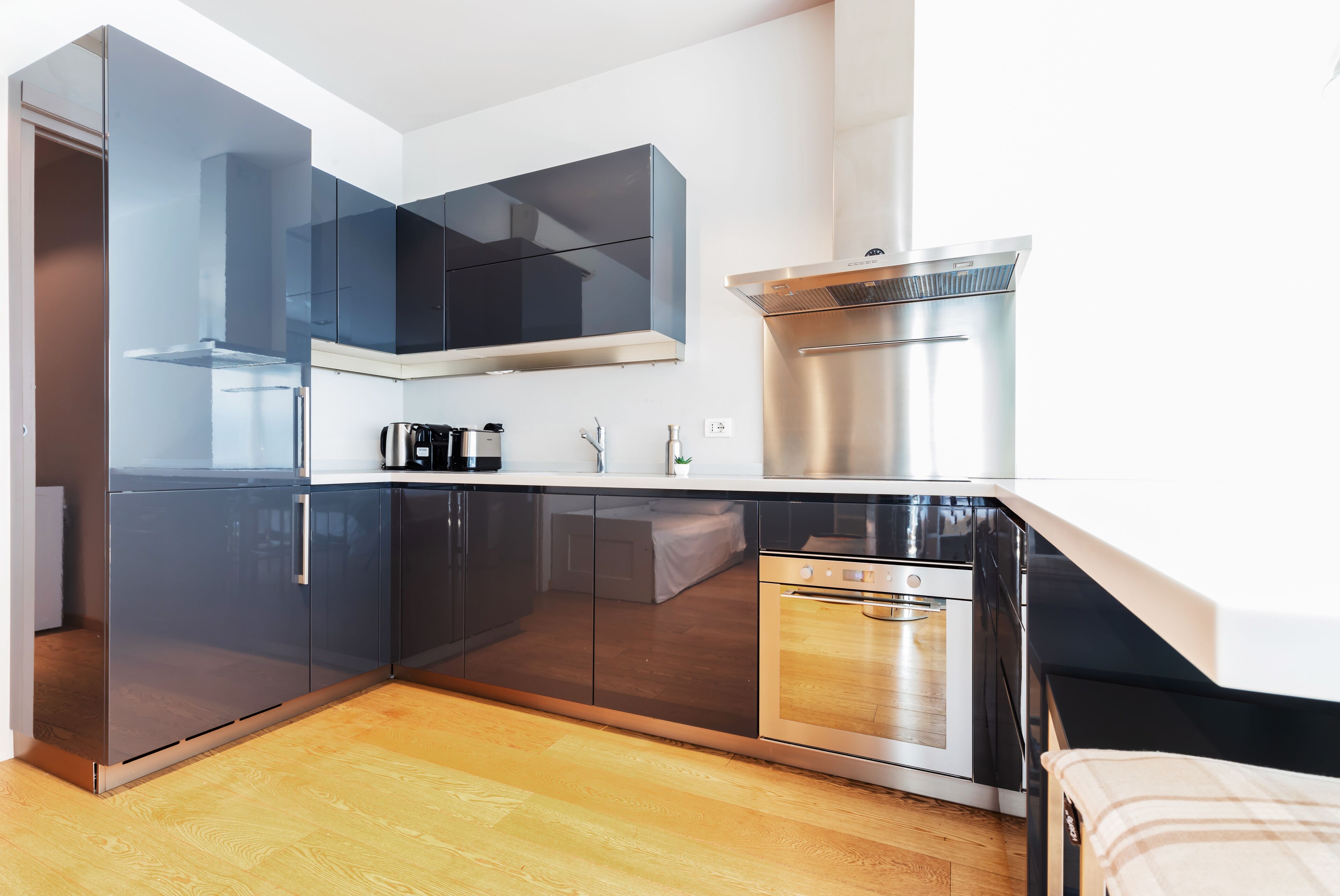 Una cocina moderna con horno empotrado, electrodomésticos de acero inoxidable y un armario con puerta de cristal.