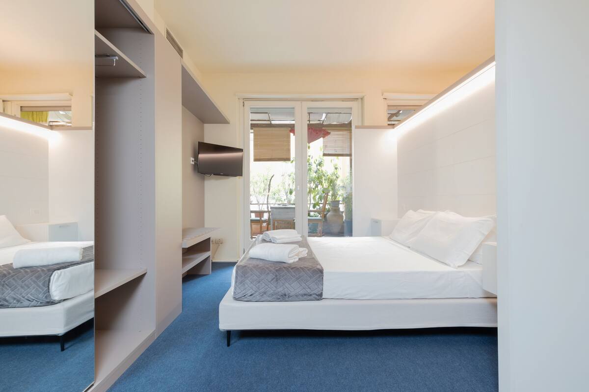 A modern hotel room with a large bed, a desk, and a TV.