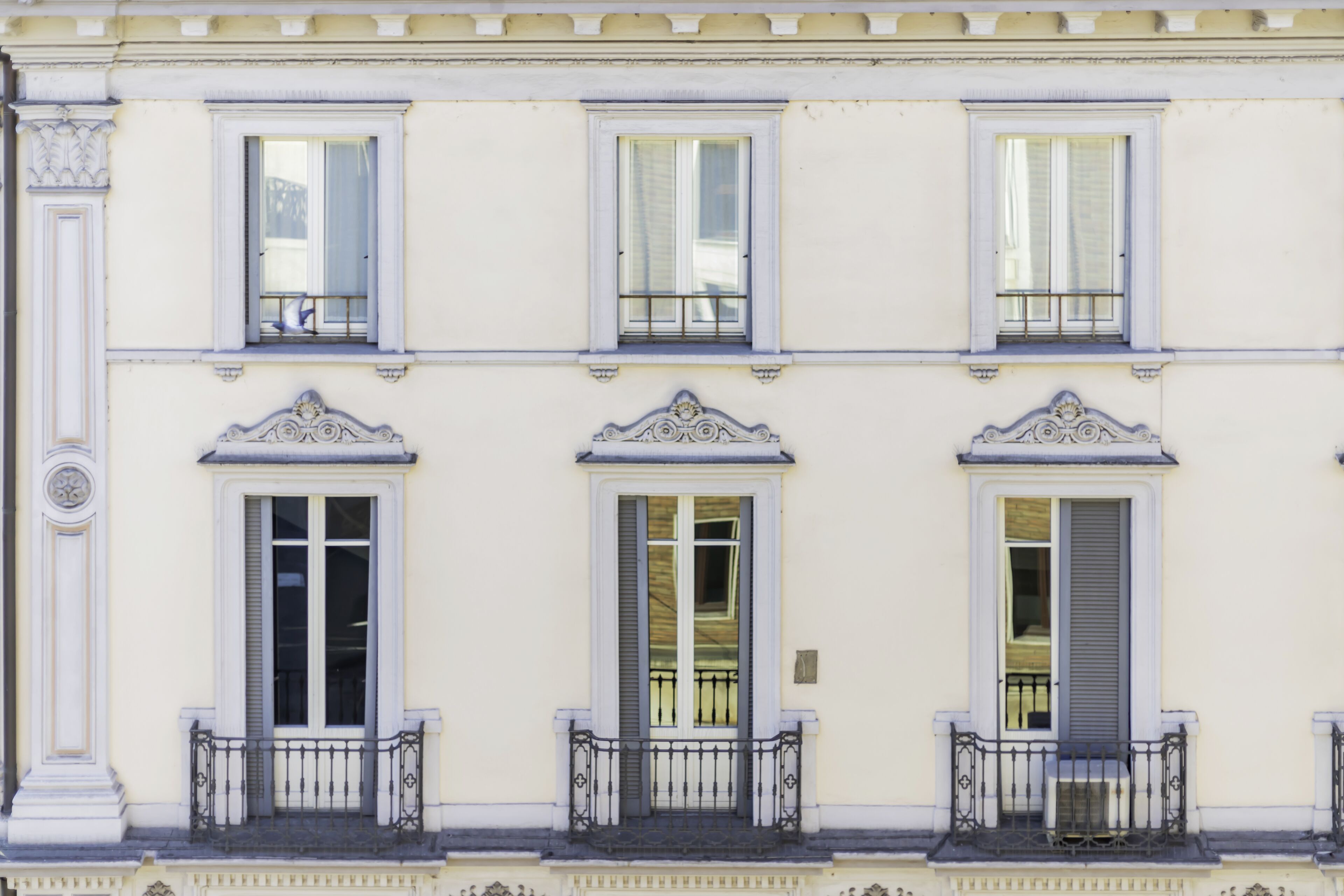 A building with three windows, each with a balcony and decorative moldings.