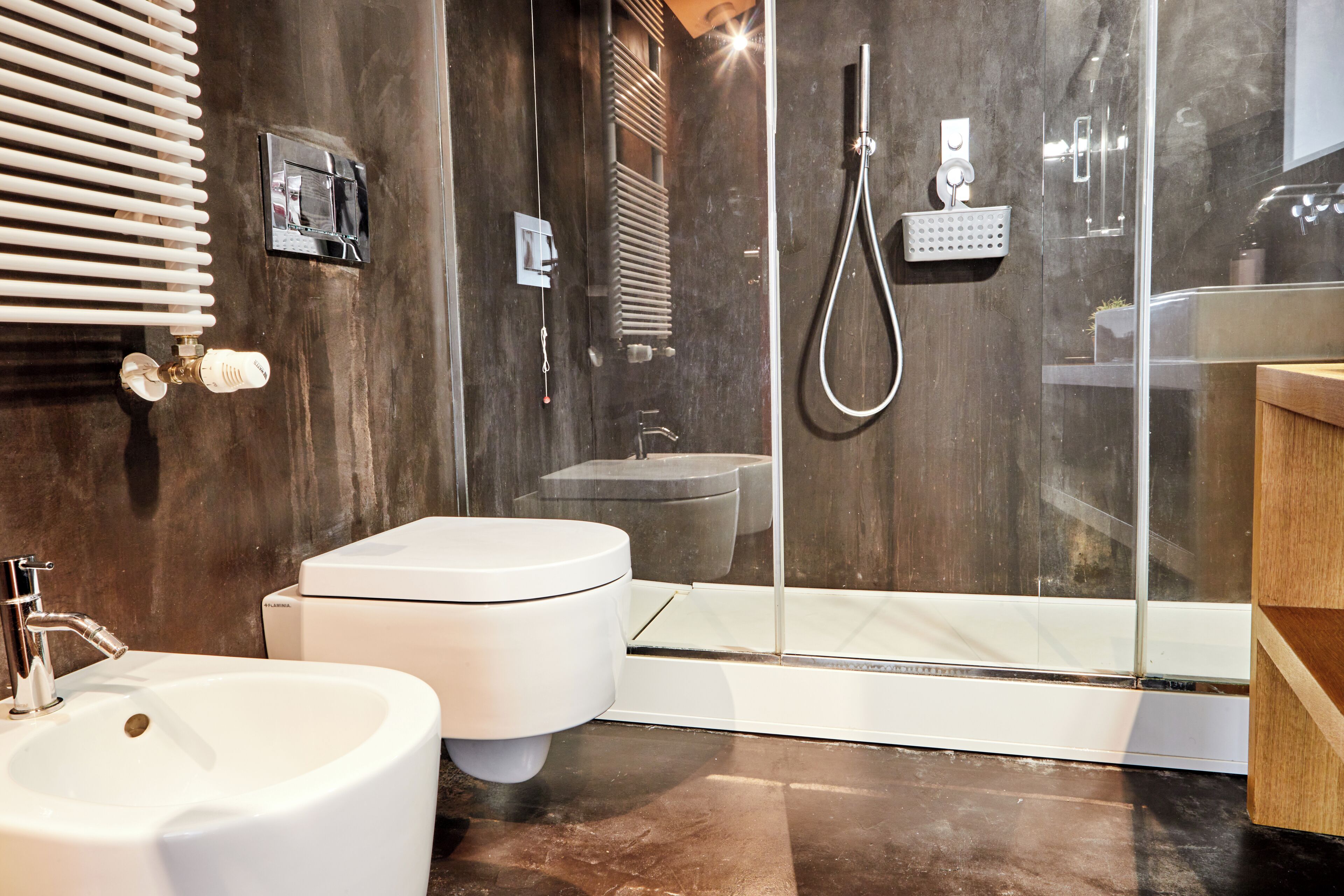 A modern bathroom with a glass-enclosed shower, a white toilet, and a bidet.