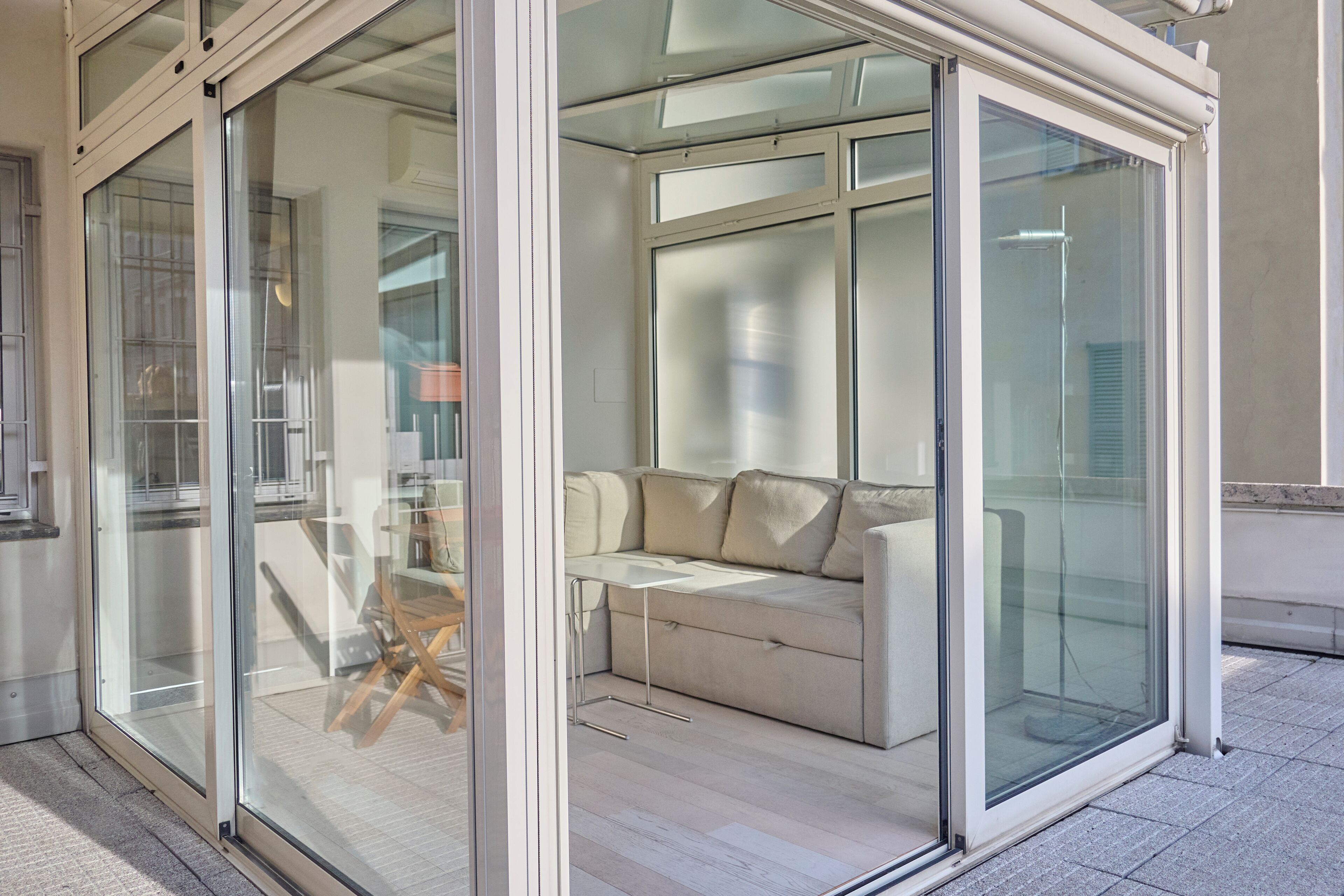 A modern interior with a glass partition, a sofa, and a table.