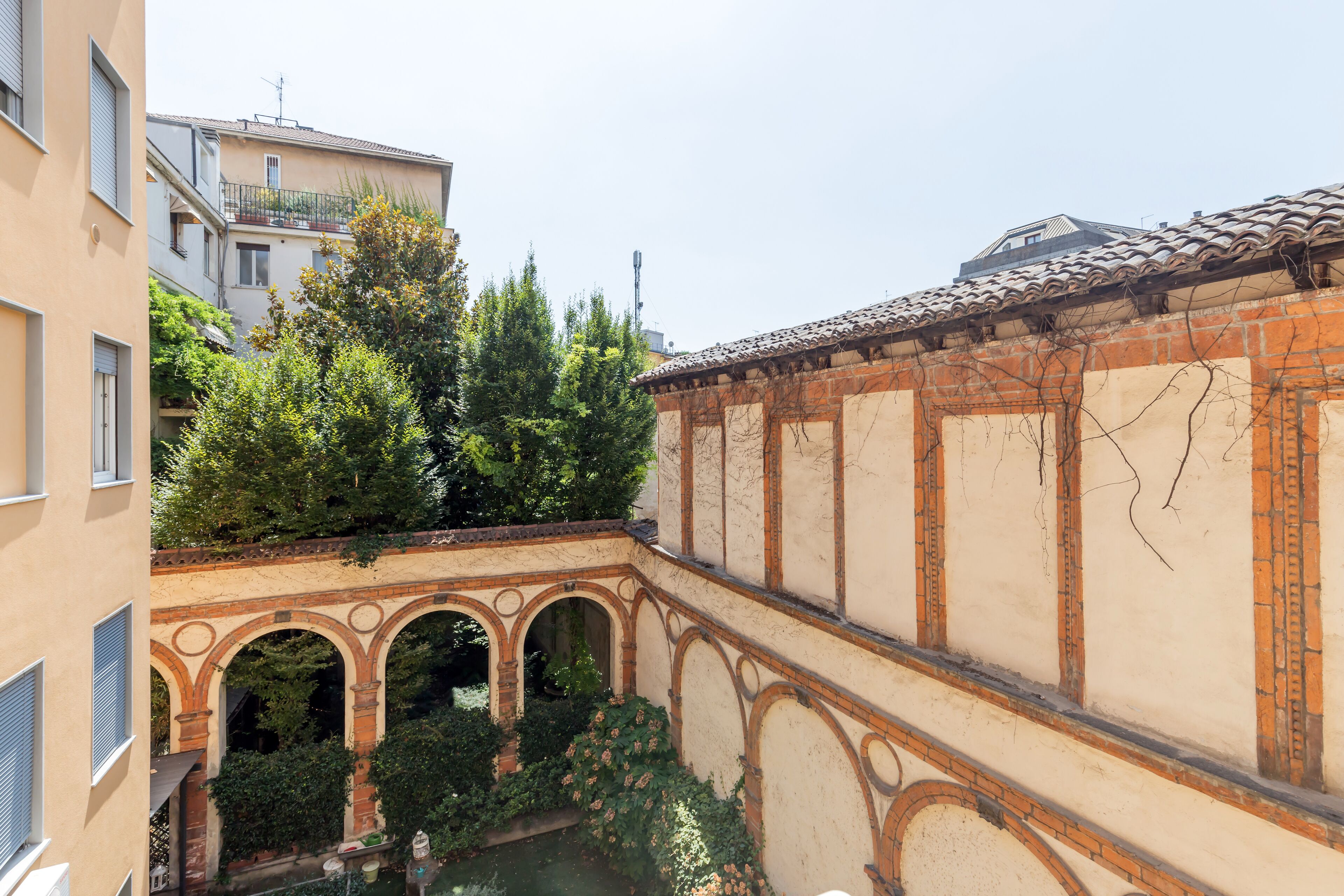 A courtyard with arched walkways, a water feature, and surrounding greenery.