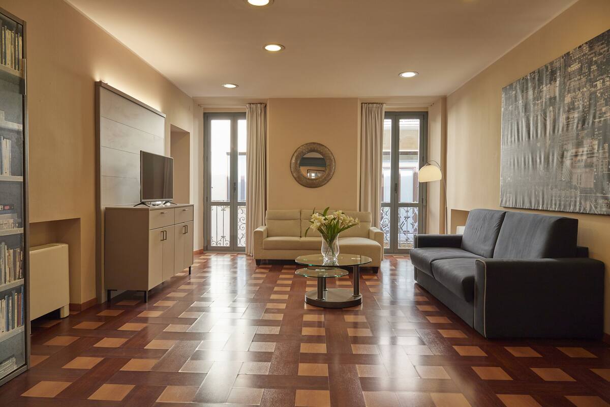A modern living room with a sofa, armchair, coffee table, and a TV.