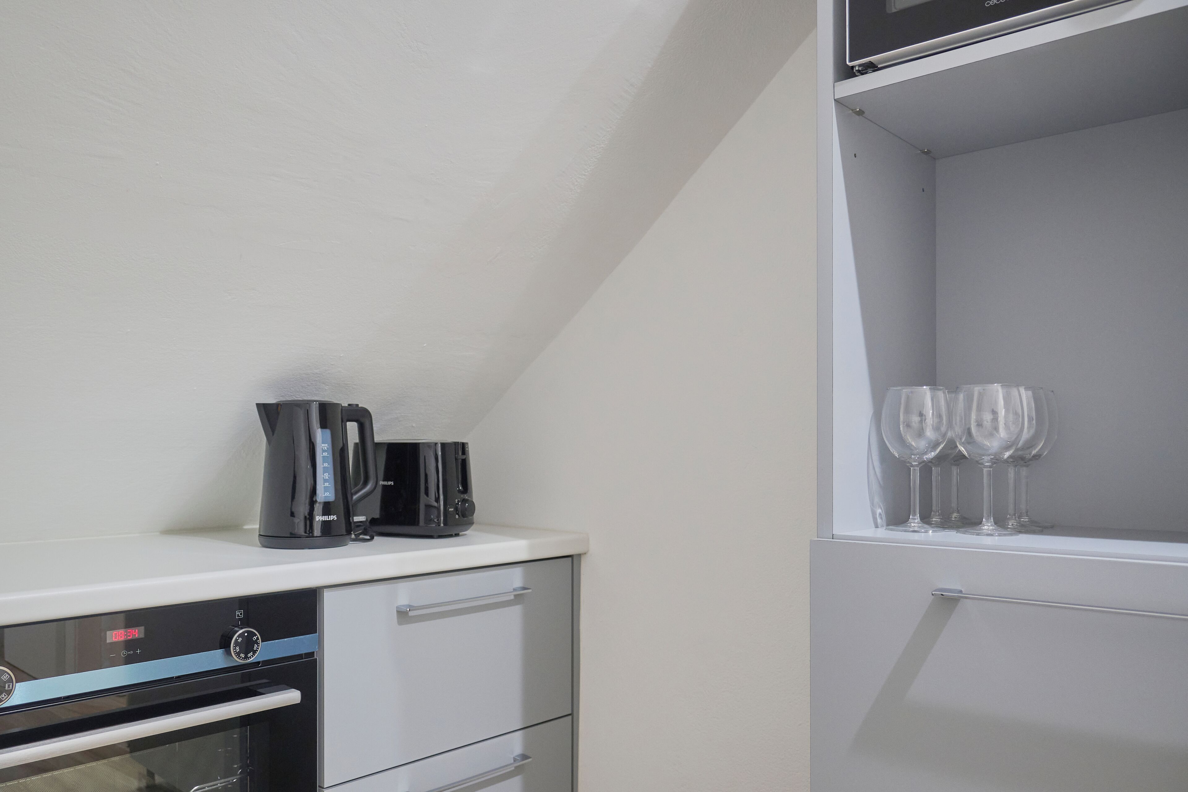 A kitchenette with a coffee maker, a toaster, and a wine glass rack.