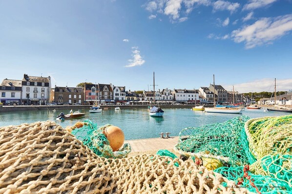 A harbor with boats and fishing nets, buildings along the waterfront, and a clear sky. - Charming fisherman's cottage in the town centre (Saint-Philibert)