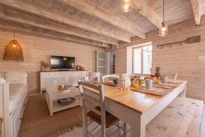 Une pièce chaleureuse avec un plafond en bois, une table à manger avec des chaises, un téléviseur et une fenêtre.