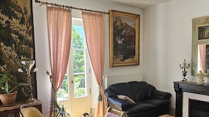 Un salon avec un canapé en cuir noir, deux fauteuils à motifs, une petite table ronde et un grand tapis à motifs.
