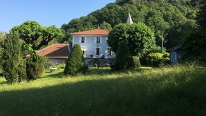 Un bâtiment blanc surmonté d’un toit rouge, entouré d’une végétation luxuriante et d’arbres.