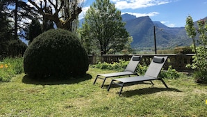 Deux fauteuils de jardin placés dans un jardin offrant une vue sur les montagnes.