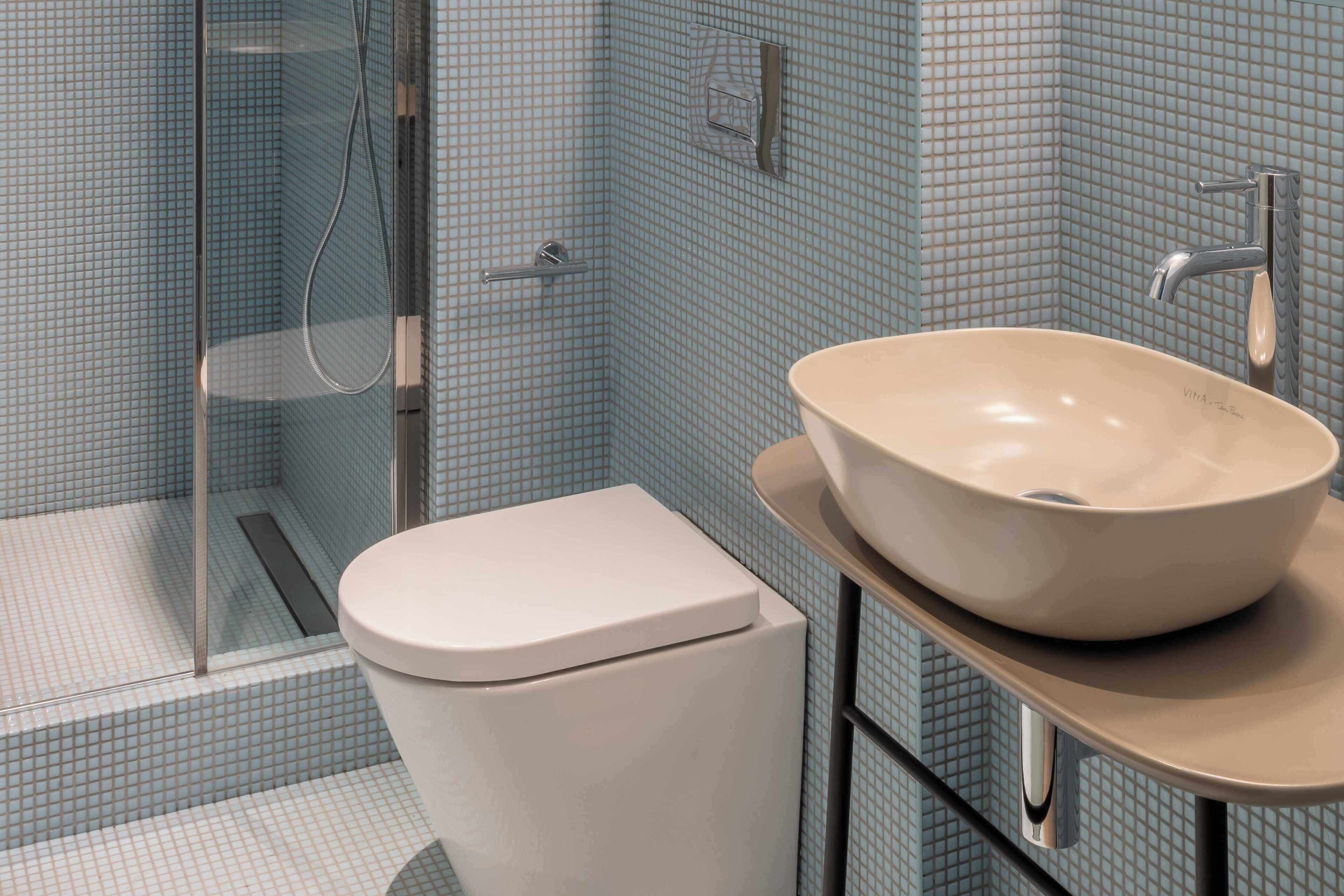 A bathroom with a white toilet, a beige sink, and a shower area.