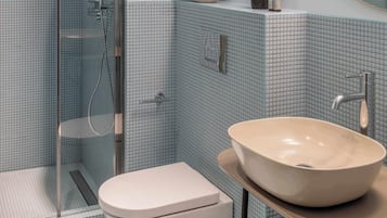 Un baño con cabina de ducha de vidrio, inodoro y un lavabo tipo cuenca.