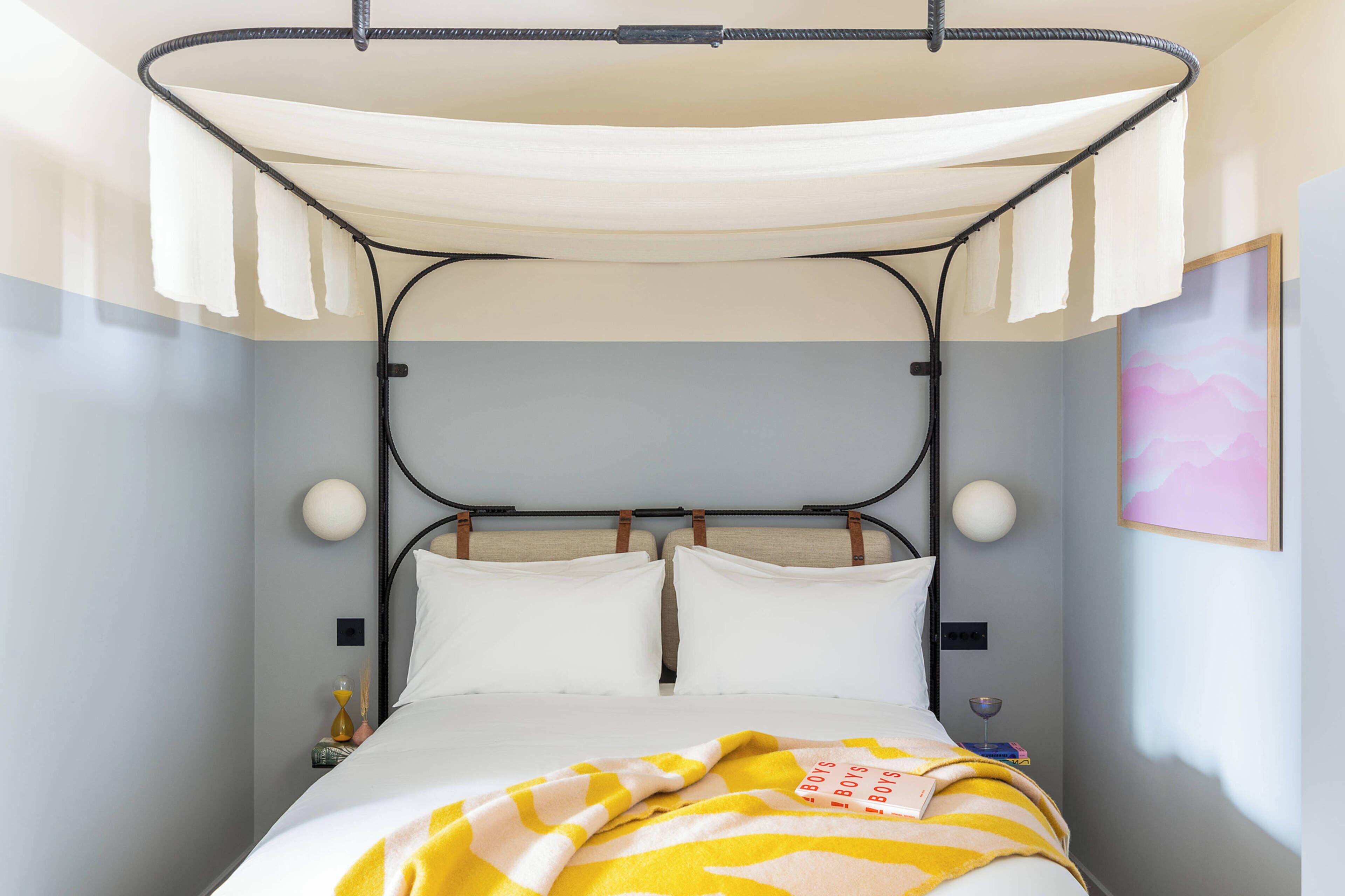 A bed with a canopy, two bedside tables, a wall clock, and a framed picture.