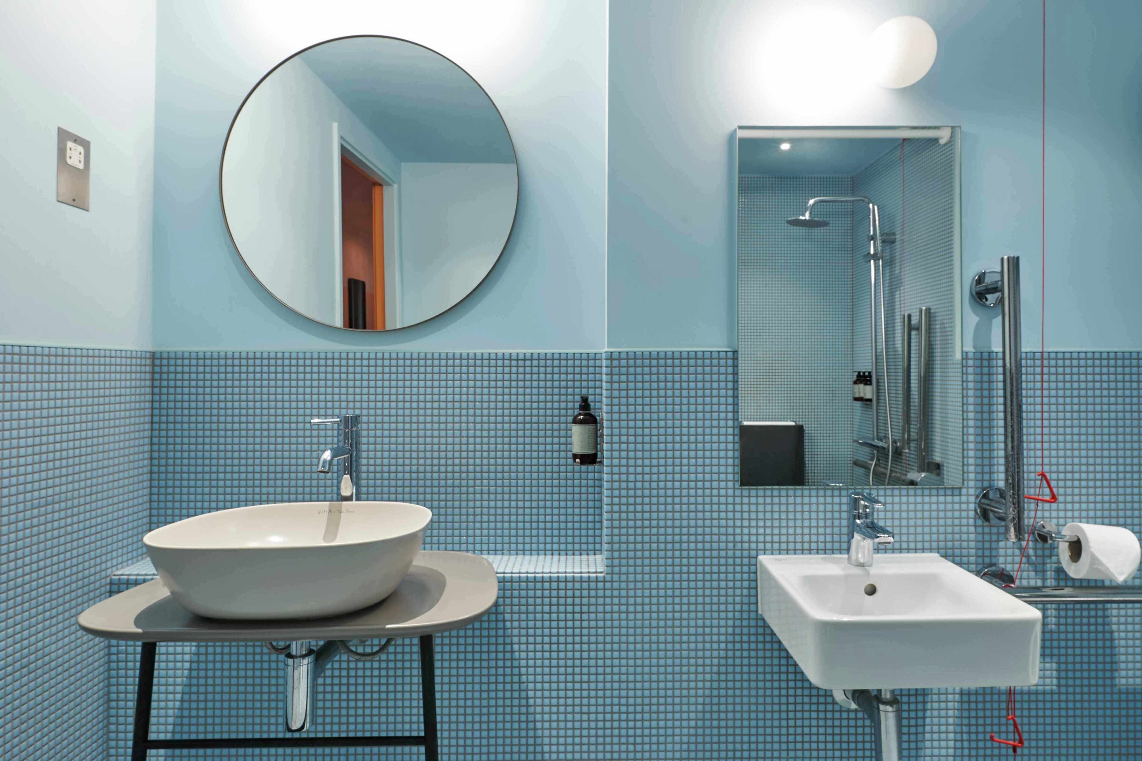 A bathroom with a round mirror, a sink, and a shower area.