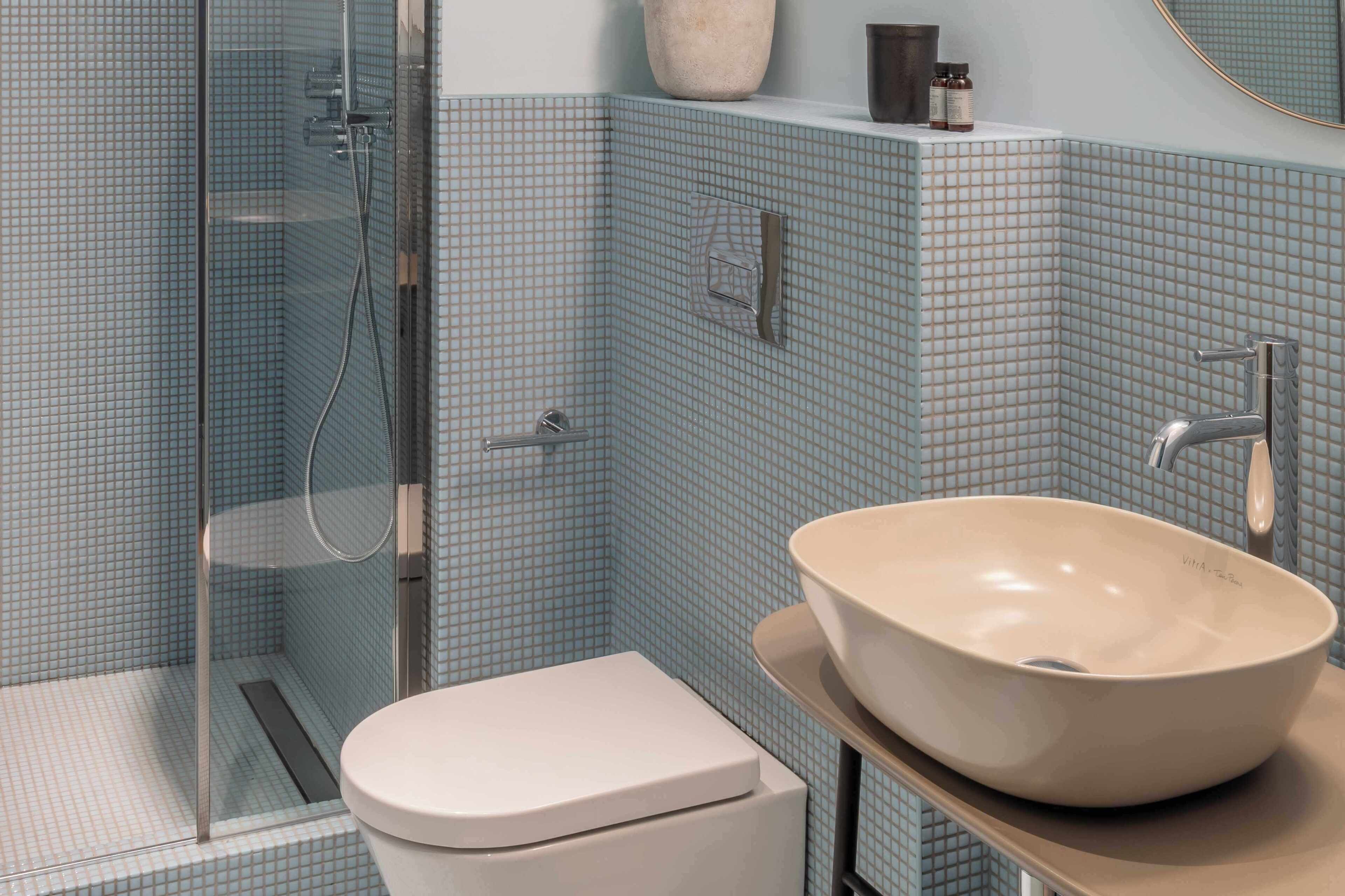 Baño con cabina de ducha de vidrio, inodoro y lavabo sobre encimera.