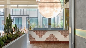A spacious lobby with a large circular light fixture, a patterned wall, and a view of the city through large windows. - Bermonds Locke, Tower Bridge (London)