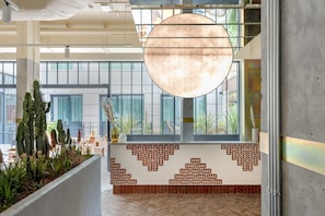 Un vestíbulo amplio con una gran lámpara circular, un papel tapiz decorativo y vistas de la ciudad a través de amplias ventanas.