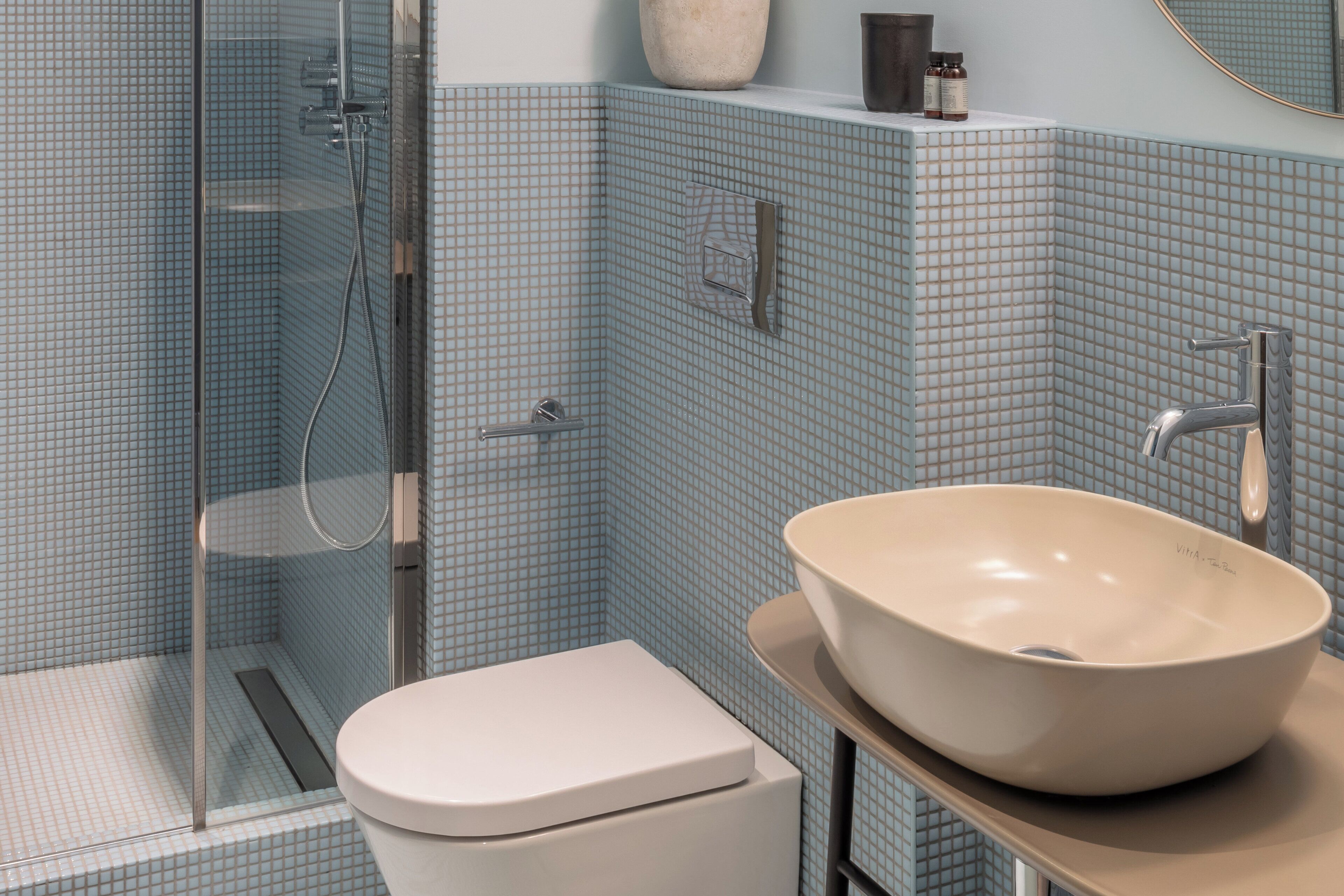 A bathroom with a glass shower enclosure, a white toilet, and a beige sink with a modern faucet.