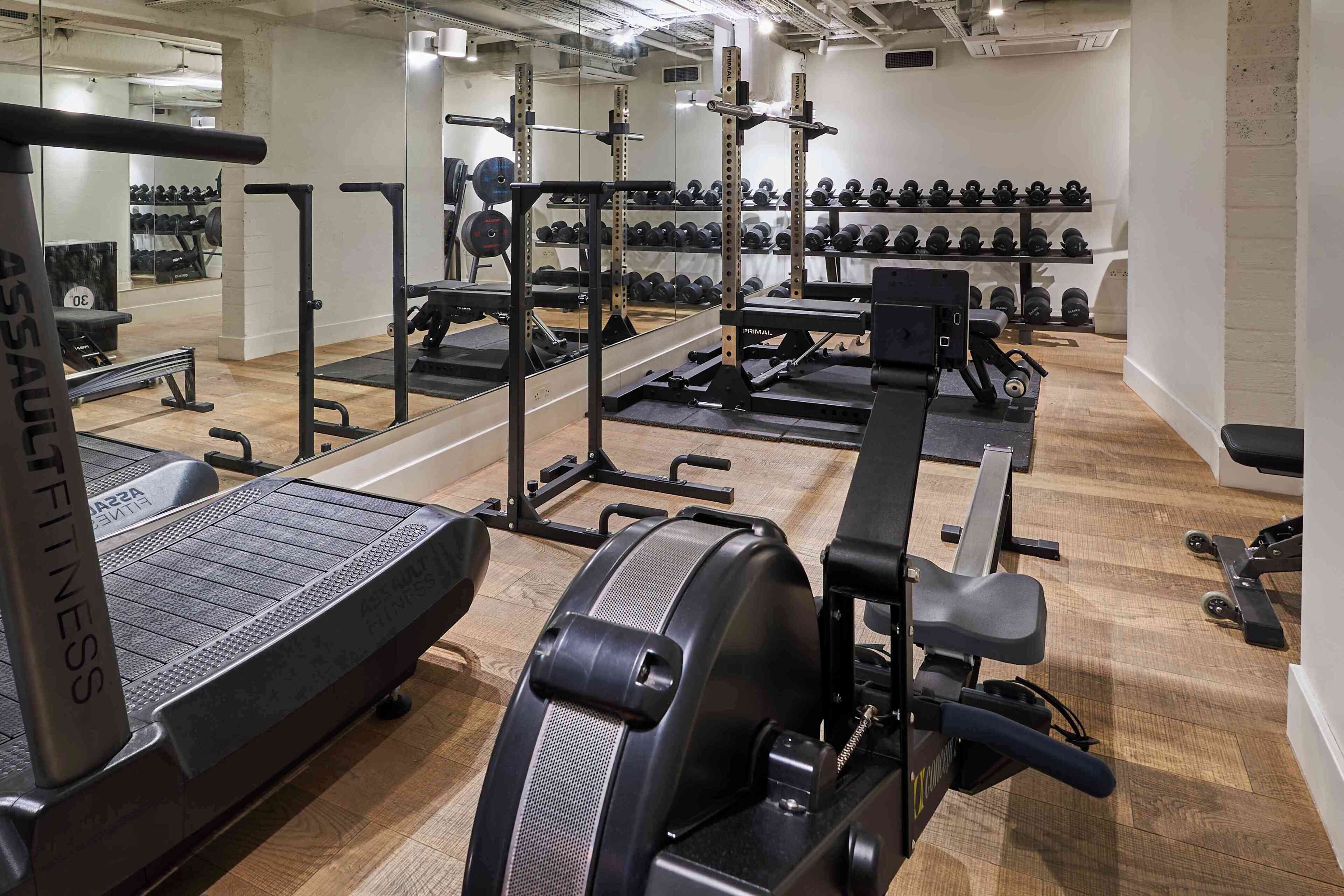 A gym with exercise equipment, weight racks, and treadmills.