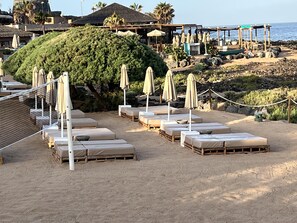 Een strandresort met ligbedden, parasols en uitzicht op de oceaan.