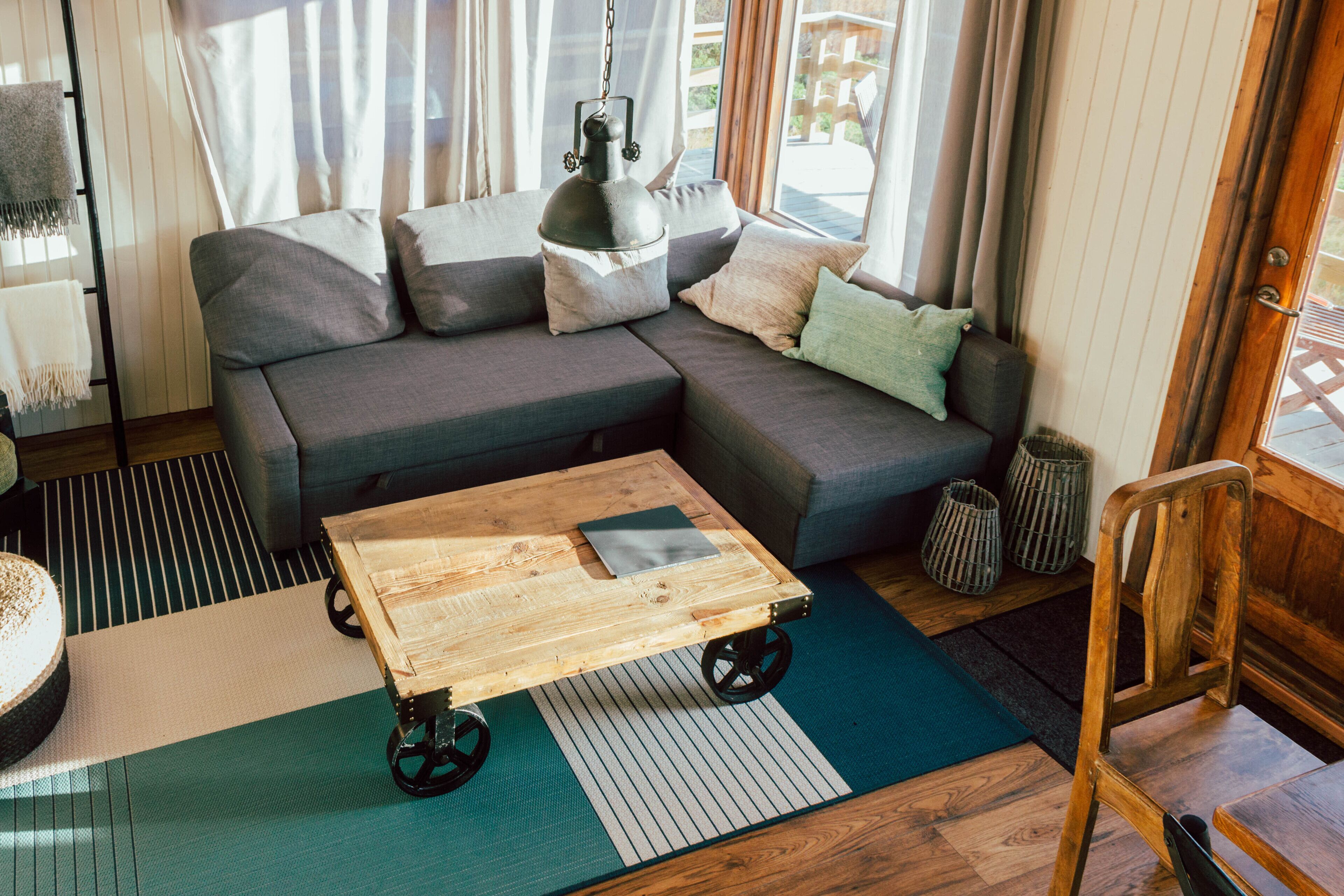 En moderne stue med en modulsofa, et træsofabord på hjul, en lille måtte og en træstol.