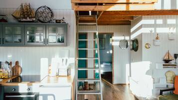 Una cocina con armarios de madera, una escalera y un comedor con mesa y sillas.