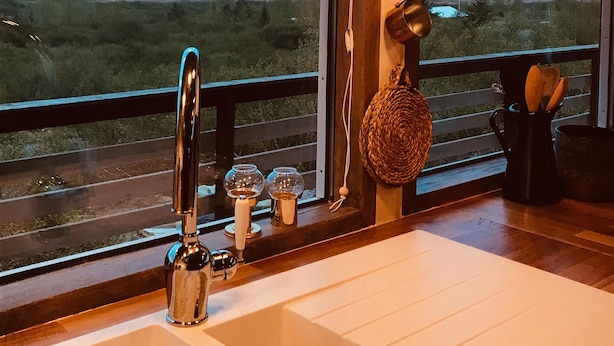 A kitchen with a large window, a sink, and hanging lights. - Múlakot Cosy Cabins (Borgarbyggd)
