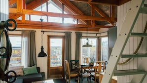A cozy cabin interior with a wooden dining table, chairs, a sofa, and a staircase. - Múlakot Cosy Cabins (Borgarbyggd)