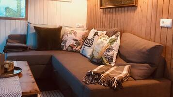 Un salon chaleureux avec un canapé d’angle, une table basse en bois et un tableau accroché au mur.