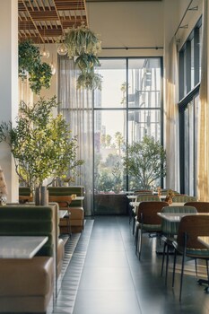 A bar area with a long counter, multiple seating options, and a view of the landscape. at The Glenmark, Glendale, a Tribute Portfolio Hotel