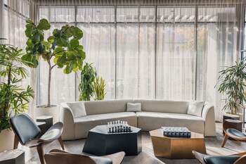 A modern lobby with a grey sofa, an orange chair, and a wooden partition. at The Glenmark, Glendale, a Tribute Portfolio Hotel