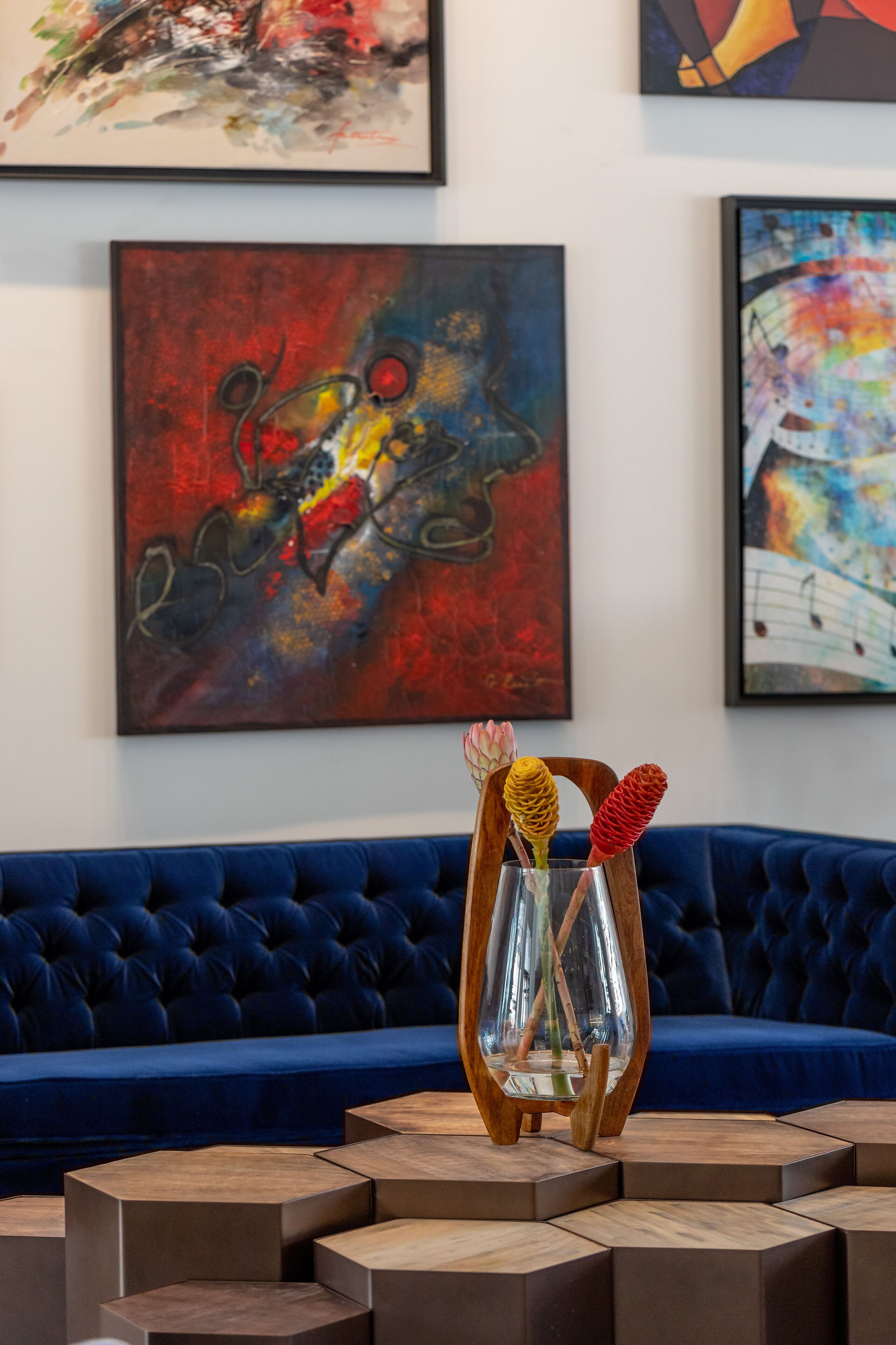 A room with a blue sofa, a wooden coffee table, and abstract paintings on the wall.