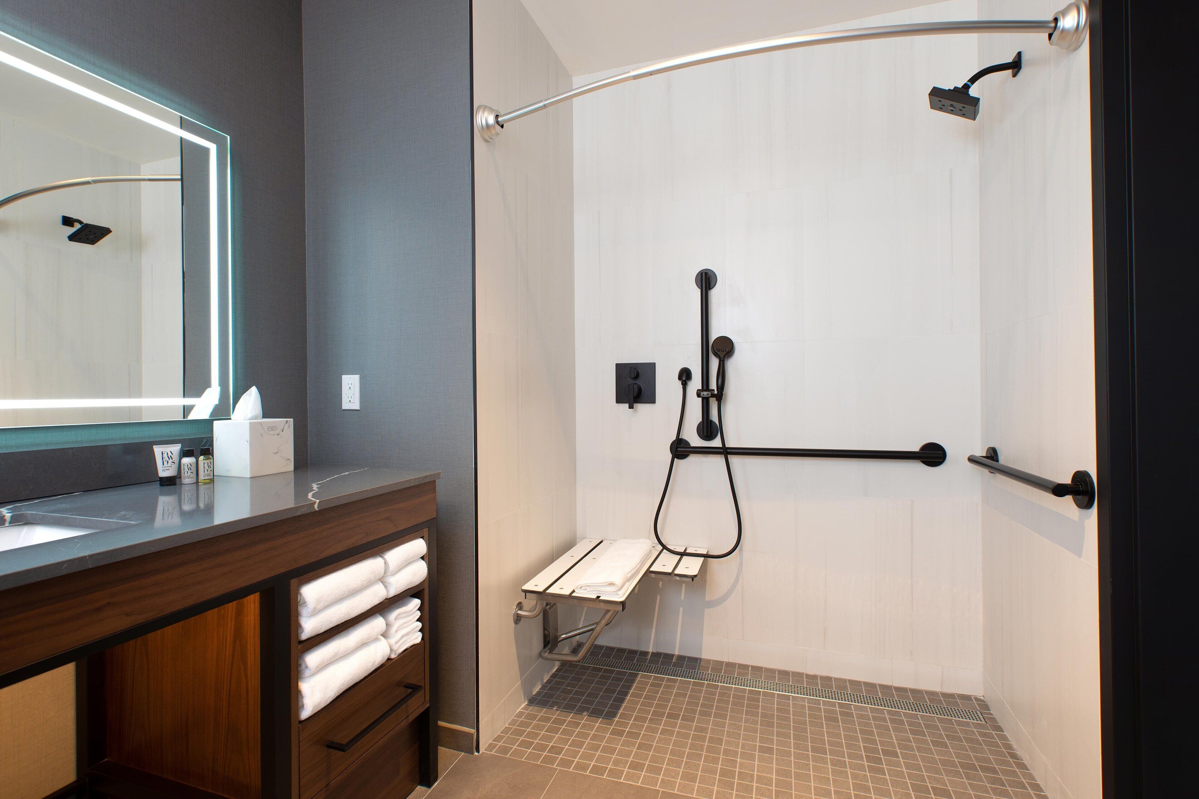 A modern bathroom with a shower, a vanity with a mirror, and a towel rack.