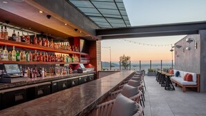 A bar area with a long counter, multiple seating options, and a view of the landscape. - The Glenmark, Glendale, a Tribute Portfolio Hotel (Glendale)