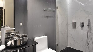 Een moderne badkamer met een douchecabine van glas, een wit toilet en rvs-wastafels.