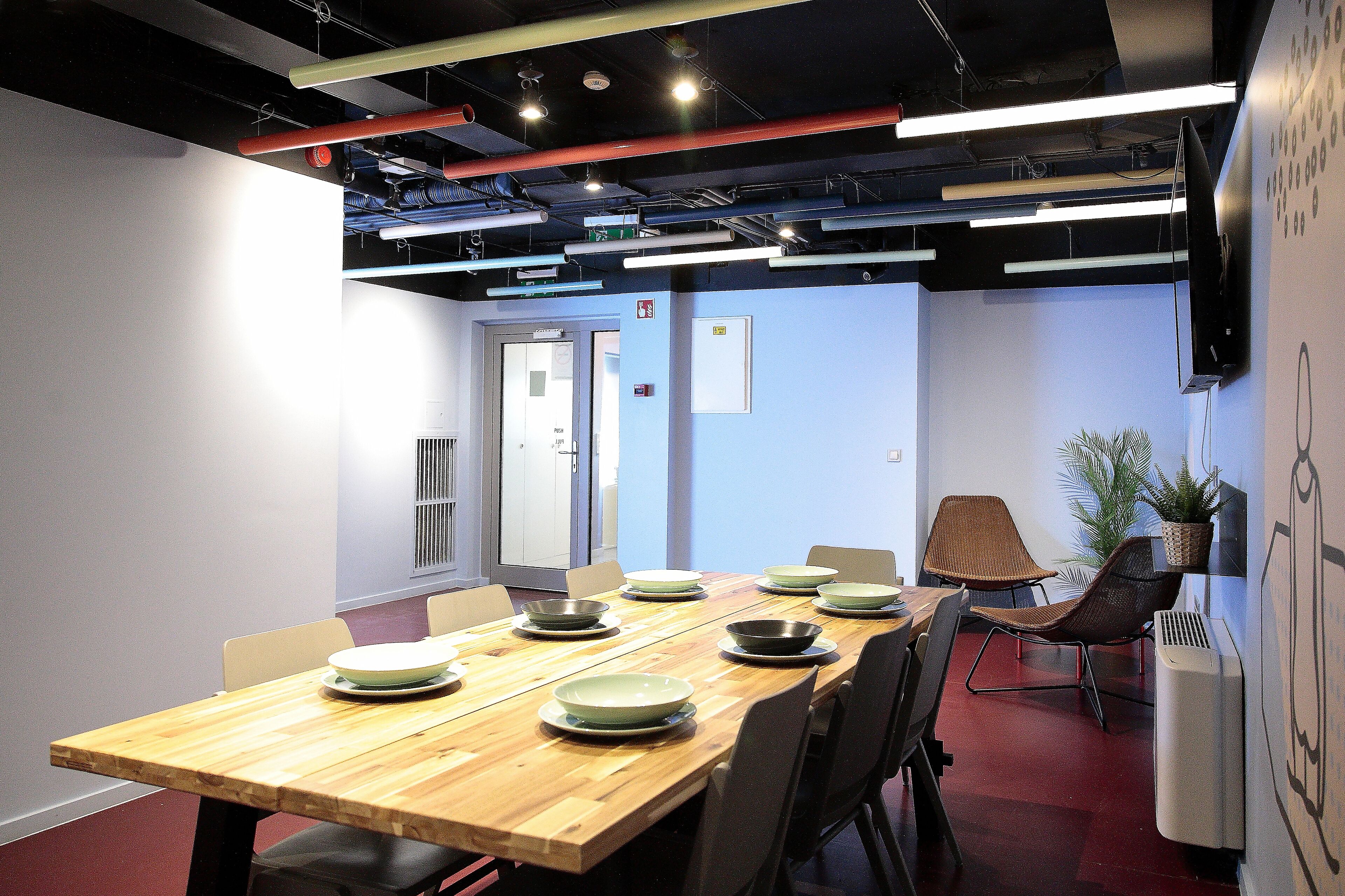 A conference room with a wooden table, chairs, and a large screen on the wall.