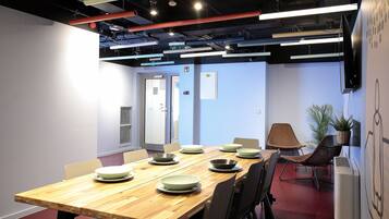A conference room with a wooden table, chairs, and a large screen on the wall.