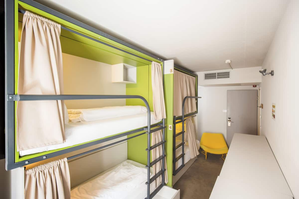 Une chambre avec un lit superposé, un mur d’accent vert, un banc jaune et un bureau blanc.