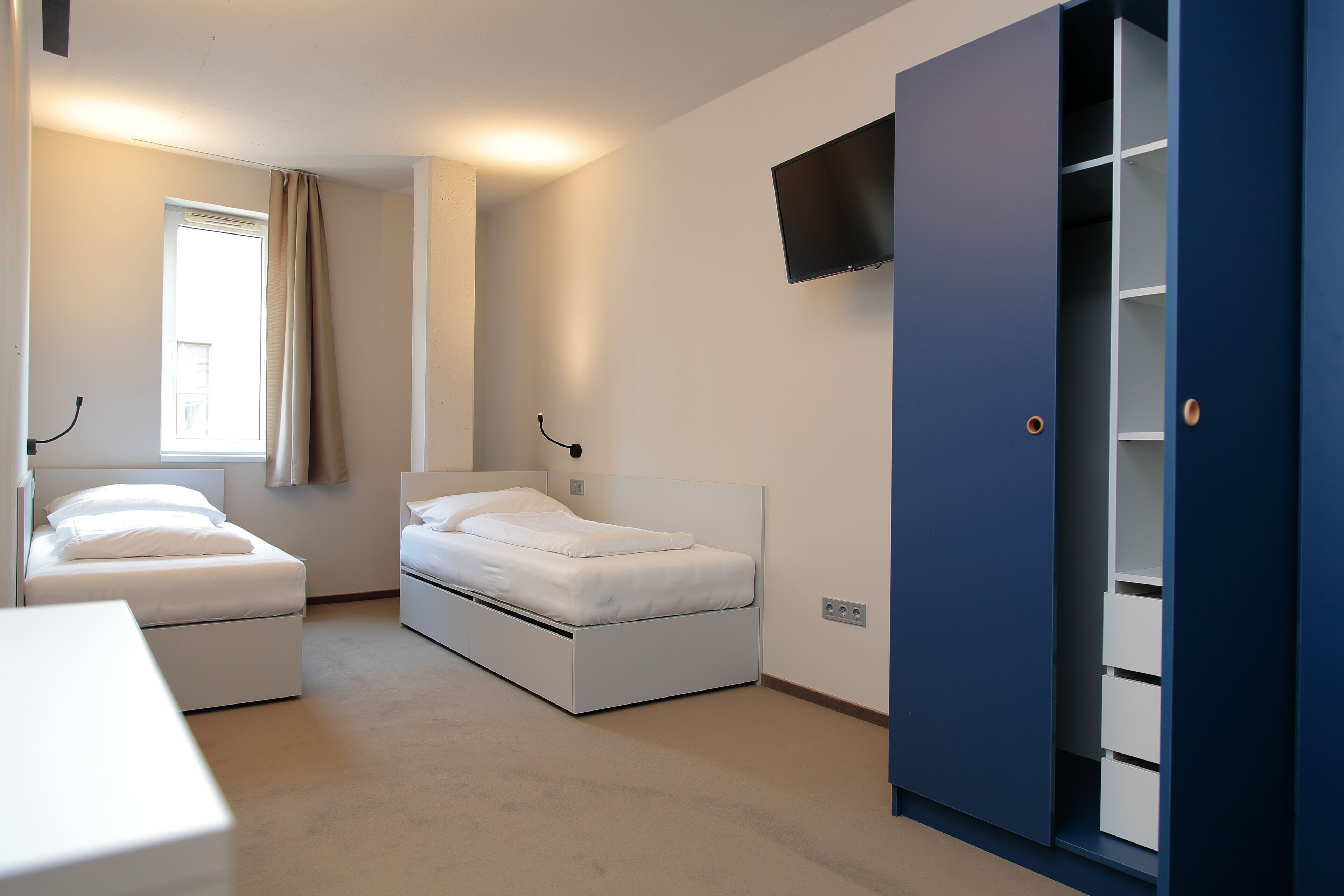 Un dormitorio con dos camas, un armario y un televisor.