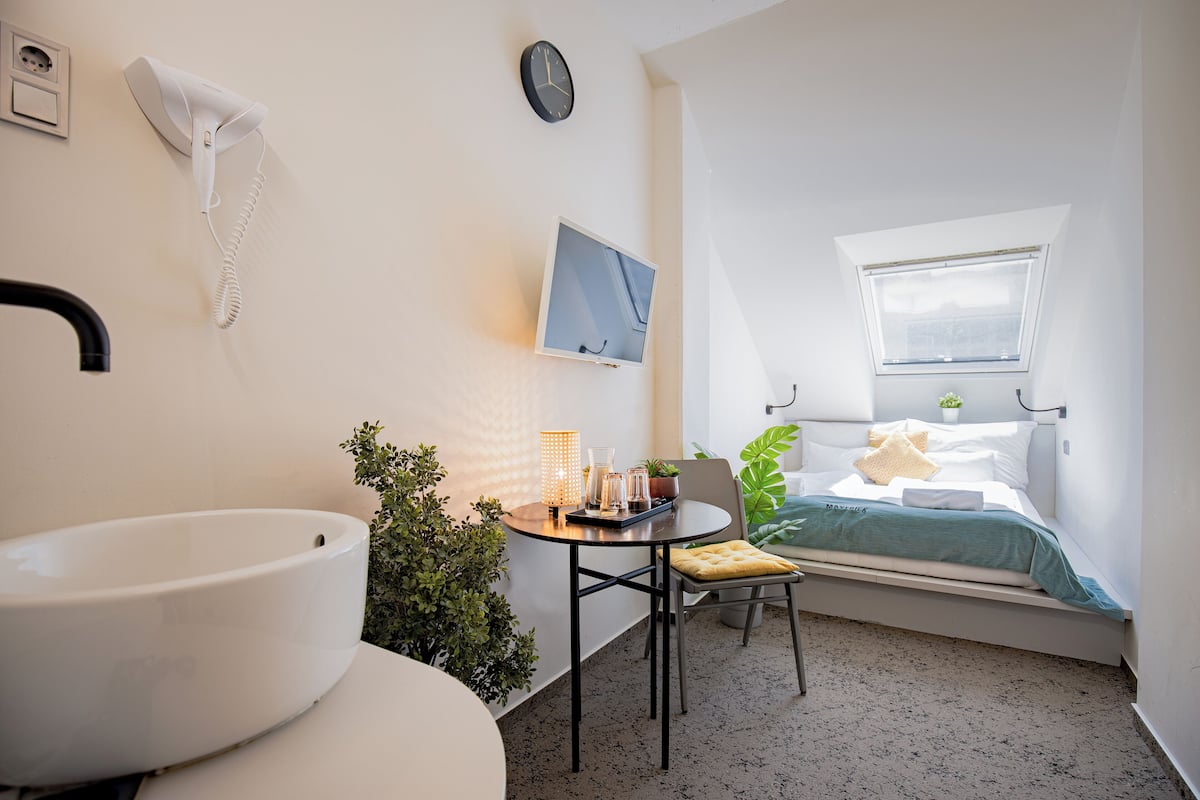 Une chambre à coucher de taille réduite, comprenant un lit, une table de chevet et une fenêtre.