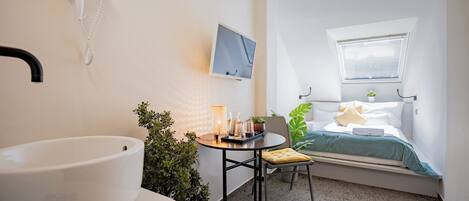 A compact bedroom with a bed, bedside table, and a window.