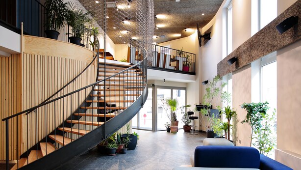 A modern interior with a spiral staircase, wooden paneling, and multiple potted plants. - Maverick Central Market (Budapest)