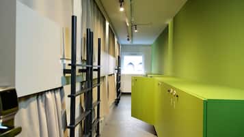 A corridor with bunk beds, a green storage unit, and a window with natural light.
