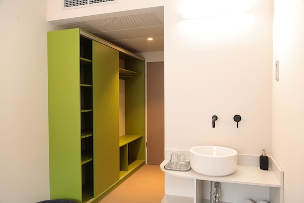 Une salle de bain moderne avec un lavabo blanc, un placard de rangement vert et un meuble-lavabo blanc.