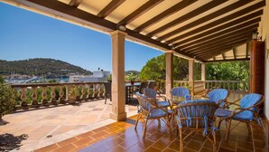 A covered outdoor patio with wicker furniture, a tiled floor, and a view of a coastal town. - Villa overlooking the Port of Andratx with private pool (Port D'Andratx)