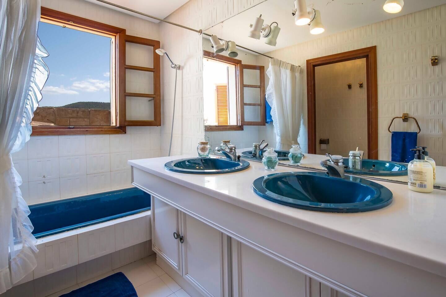 Une salle de bain avec deux lavabos, une baignoire et un grand miroir.