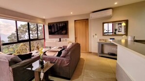 Ein modernes Wohnzimmer mit einer Couch, einem Glastisch und Blick ins Freie.
