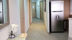 Ein Flur mit einem Kühlschrank, einer Mülltonne und einer Bank mit einem Topf-Orchideen-Pflanz.