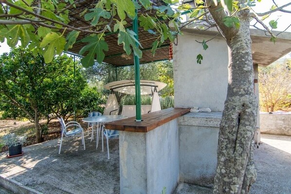 An outdoor patio area with a concrete table and chairs, a pergola with green foliage, and a stone bench under a shaded structure. - Apartment in Slatine with Terrace, Air condition, WIFI (4789-1) (Slatine)