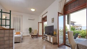 A spacious living area with a bed, a TV, a wooden entertainment unit, and a balcony with a view. - Apartment in Slatine with Terrace, Air condition, WIFI (4789-3) (Slatine)