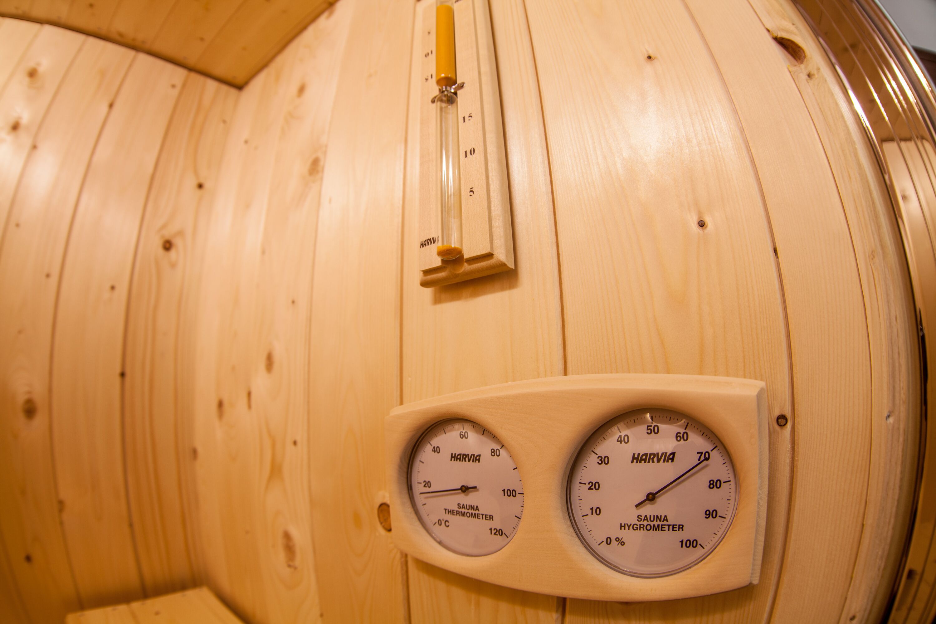 A sauna with wooden walls, a thermometer, and two gauges for temperature and humidity.